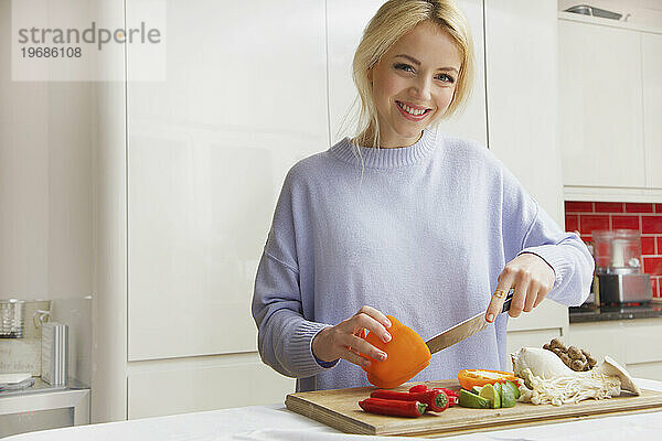 Lächelnde Frau  die Gemüse zubereitet