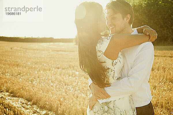 Lächelndes Paar  das sich auf einem Feld umarmt