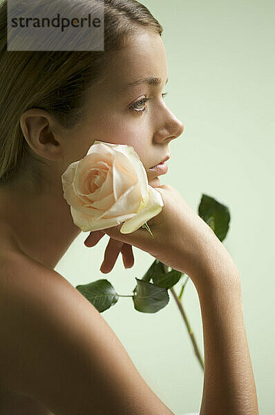 Profil einer jungen Frau  die eine Rose hält