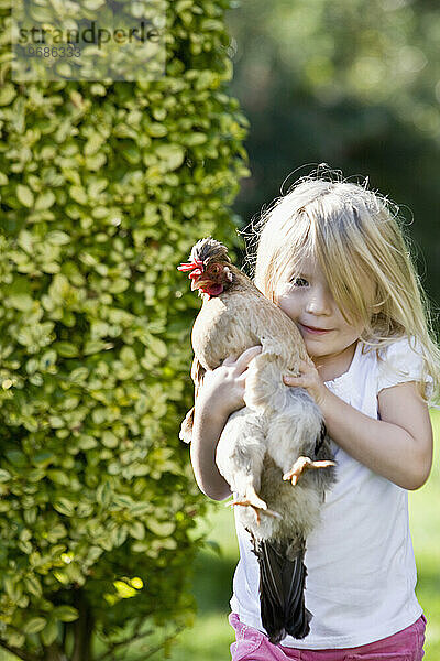 Junges Mädchen hält ein Huhn im Arm