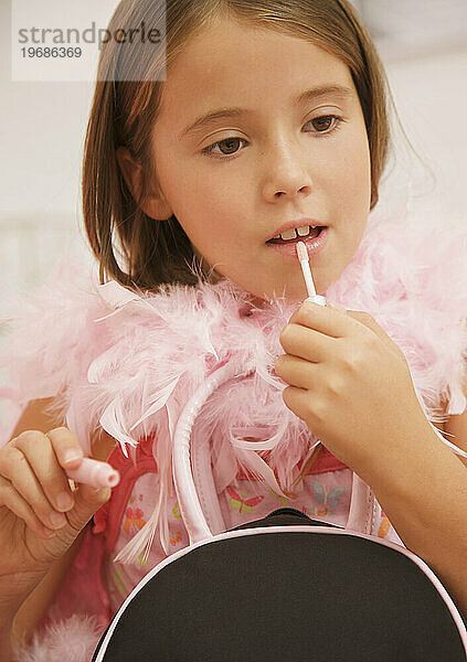 Mädchen trägt eine rosa Federboa und trägt Lipgloss auf