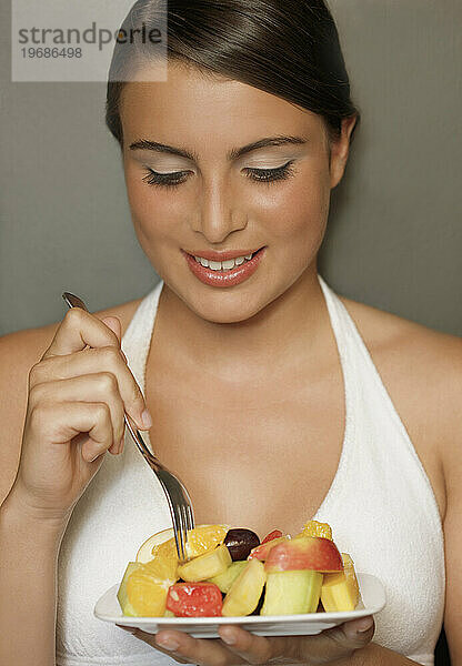 Lächelnde junge Frau  die einen Obstsalat isst