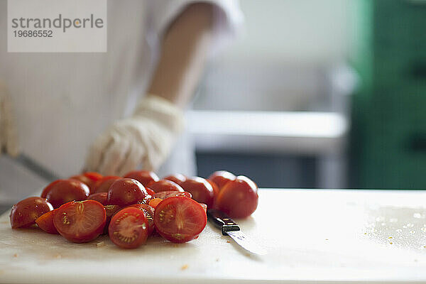 Nahaufnahme eines Arbeiters  der frische Tomaten schneidet