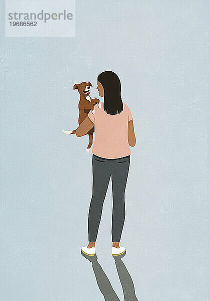 Woman holding happy puppy dog on blue background