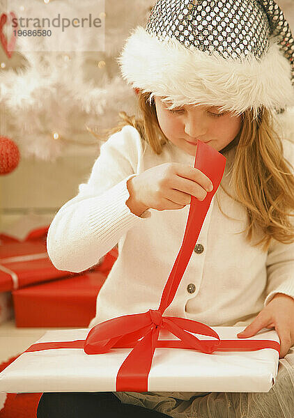 Mädchen mit Pelzmütze packt ein Weihnachtsgeschenk aus