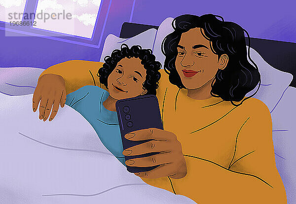 Glückliche  liebevolle Mutter und Sohn kuscheln im Bett und machen ein Selfie mit dem Smartphone