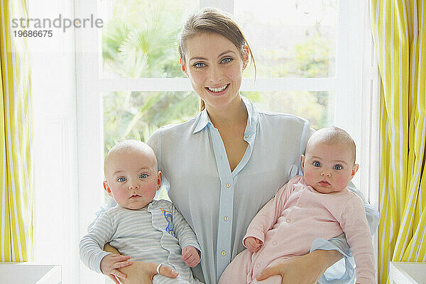 Lächelnde Mutter hält Zwillingsbabys