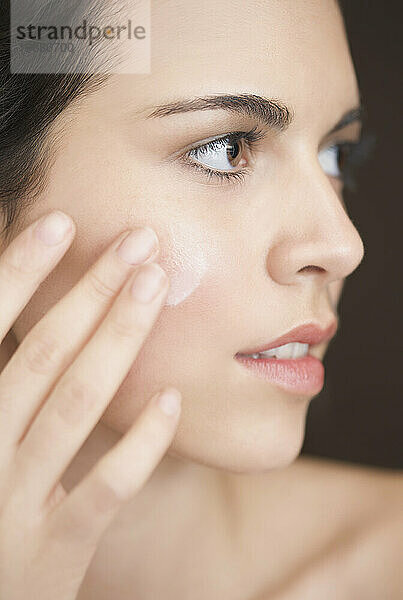 Nahaufnahme einer Frau  die Feuchtigkeitscreme auf ihr Gesicht aufträgt