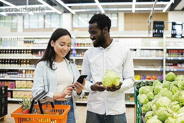 Glückliches multiethnisches Paar bei der Auswahl von Waren im Supermarkt