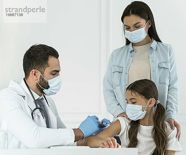 Männlicher Arzt beim Impfen eines kleinen Mädchens