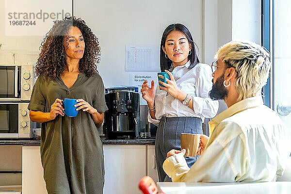 Chill Szene von drei multiethnischen Mitarbeitern beim Kaffeetrinken während einer Pause im Büro