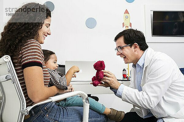 Seitenansicht Arzt spielt mit Baby Junge