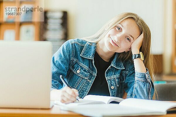 Lächelnder Teenager macht Notizen am Laptop