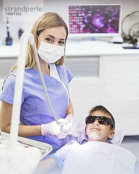 Zahnärztin steht in der Nähe eines Jungen mit Schutzbrille