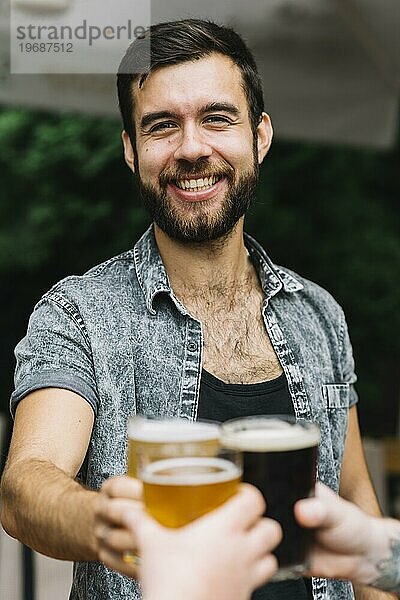 Portrait lächelnder Mann stößt mit seinem Freund auf ein Bierglas an