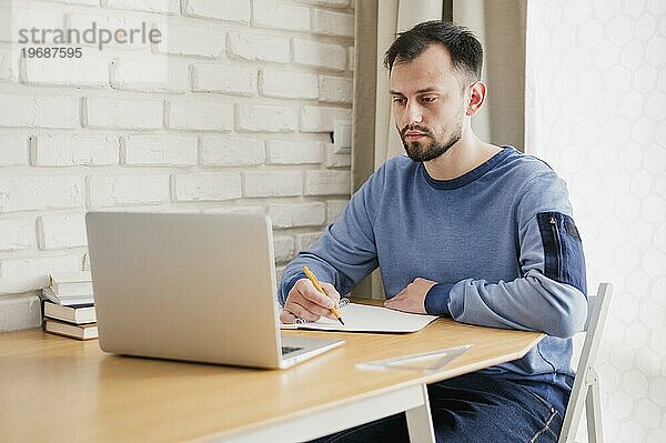 Vorderansicht Mann am Schreibtisch beim Online Lernen am Laptop
