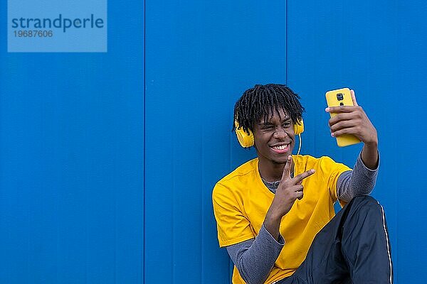 Foto mit Kopierbereich eines jungen afroamerikanischen Mannes  der Musik hört und ein Selfie im Freien macht