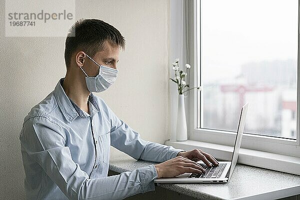 Seitenansicht Mann mit medizinischer Maske bei der Arbeit am Smartphone