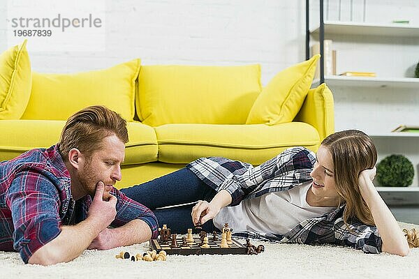 Nachdenklicher junger Mann mit lächelnder Frau beim Schachspiel