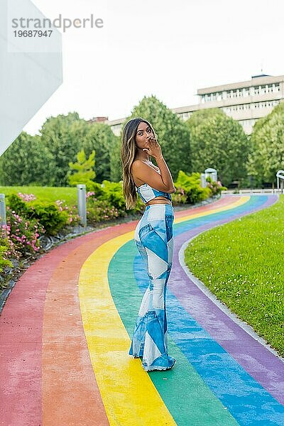 Vertikales Foto einer Frau  die einen Kuss in einem Park mit Regenbogen lgtb Pfad bläst