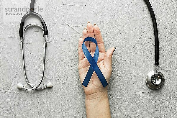 Zuschneiden der Hand mit blauem Band in der Nähe des Stethoskops