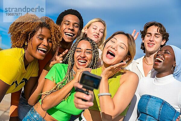 Aufgeregte multiethnische Freunde machen ein Selfie im Freien mit einer Gopro Kamera