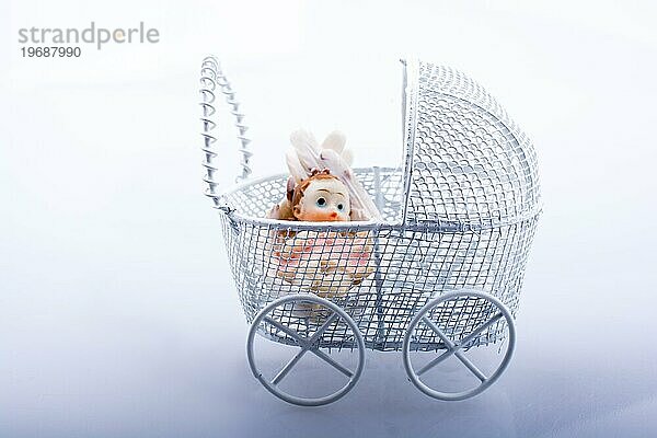 Kleine Babypuppe im Kinderwagen auf einem weißen Hintergrund