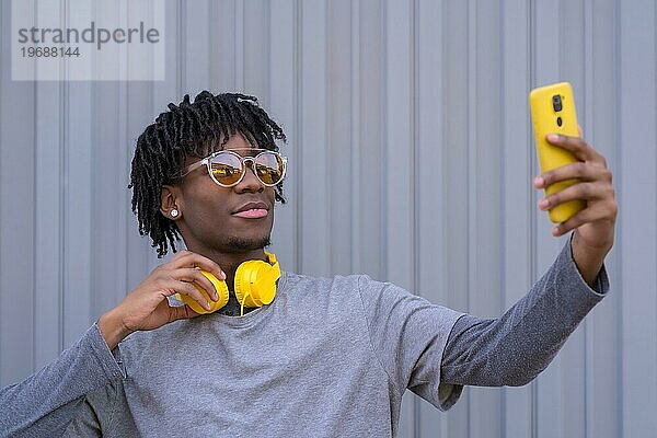 Afrikanischer cooler Mann macht ein Selfie neben einer grauen Stadtmauer