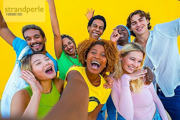 Frontalansicht von glücklichen diversen Freunden  die ein Selfie machen  lächelnd und lachend vor einem gelben Hintergrund