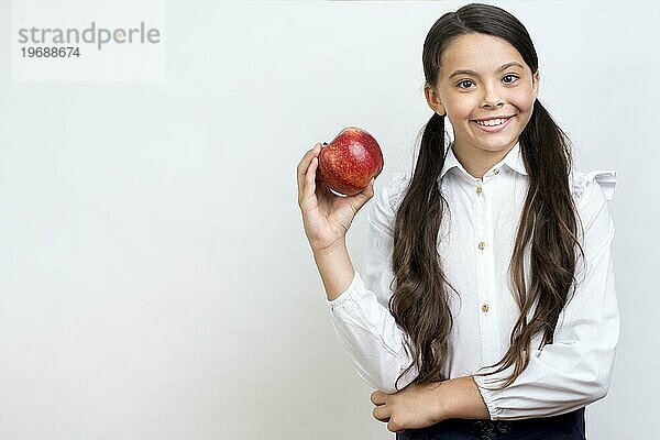 Fleißiges hispanisches Schulmädchen ißt Apfel