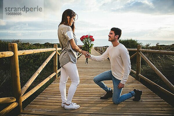 Mann kniend Übergabe Blumenstrauß Rosen Frau