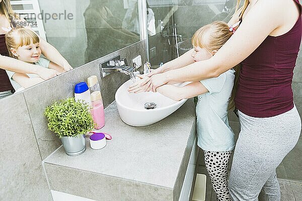 Crop Mutter hilft ihrer Tochter beim Händewaschen