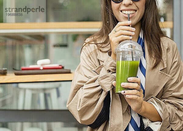 Glückliche Frau trinkt grünen Smoothie