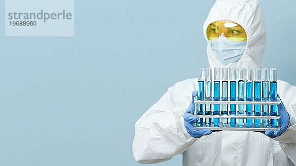 Vorderansicht eines Wissenschaftlers mit blaün Chemikalien in der Hand und Kopierraum