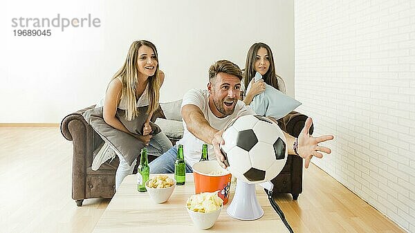 Freunde jubeln beim Fußballspielen zu Hause