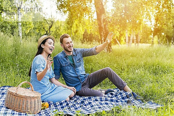 Junges glückliches Paar winkt lächelnd Picknick Natur