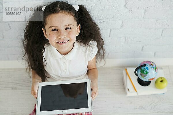 Mädchen sitzend auf dem Boden mit Tablette