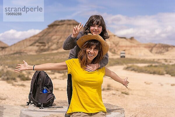 Porträt einer glücklichen Mutter und ihrer Tochter  die nach einem Trekking in der Wüste erfolgreich gestikulieren