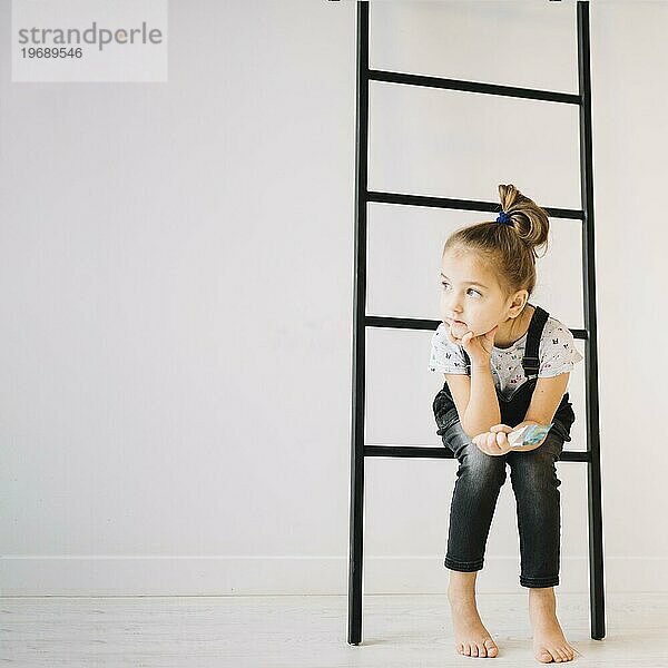 Kind mit Pinsel sitzend Leiter in der Nähe von Wand Zimmer