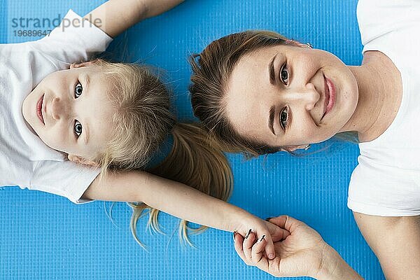 Draufsicht glückliche Mutter posiert mit Tochter Yogamatte