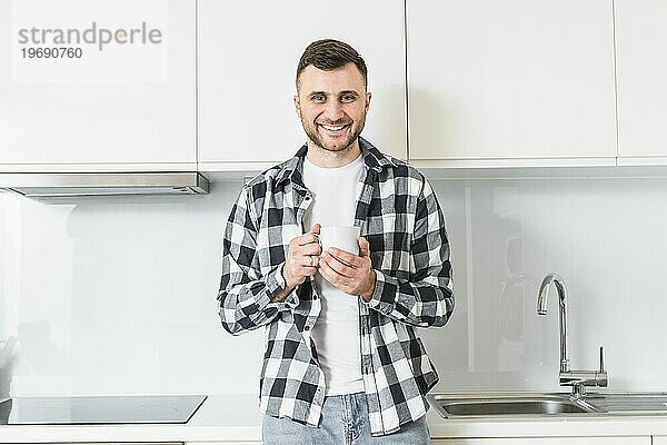 Porträt lächelnd junger Mann hält Tasse Hand suchen Kamera