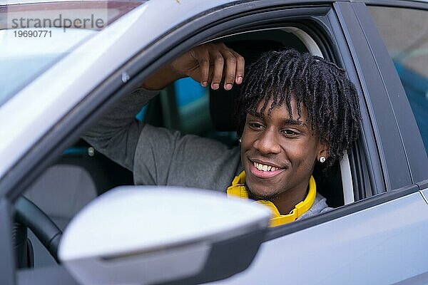 Seitenansicht Porträt eines glücklichen afrikanischen jungen Mannes sitzt in einem Auto