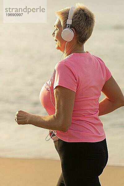Seitenansicht ältere Frau mit Kopfhörern joggen Strand