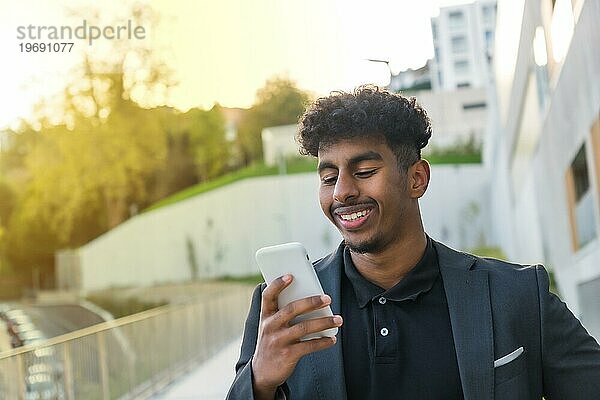 Close up Porträt eines lächelnden arabischen Geschäftsmann mit Telefon am Morgen auf der Straße