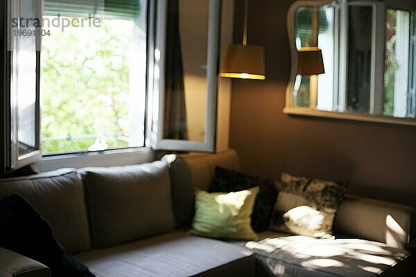 Gemütliches Wohnzimmer mit Sofa und offenem Fenster