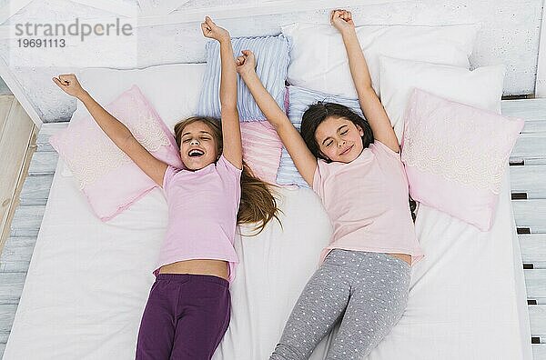 Erhöhte Ansicht zwei Mädchen strecken ihre Arme beim Aufwachen Bett