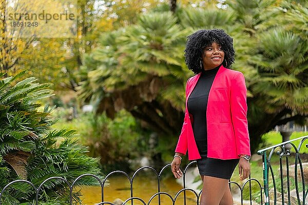 Horizontales Foto mit Kopierbereich einer afroamerikanischen Geschäftsfrau  die durch einen Park geht