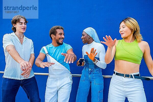 Multikulturelle junge Menschen tanzen eine musikalische Choreografie in einem blauen städtischen Raum