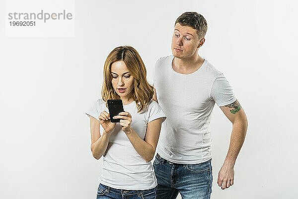 Junger Mann versucht Spionage ihre Freundin s Handy isoliert weißem Hintergrund