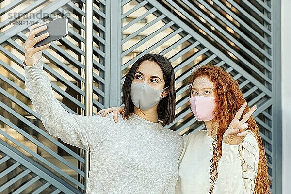 Frontansicht weibliche Freunde mit Gesichtsmasken im Freien nehmen selfie